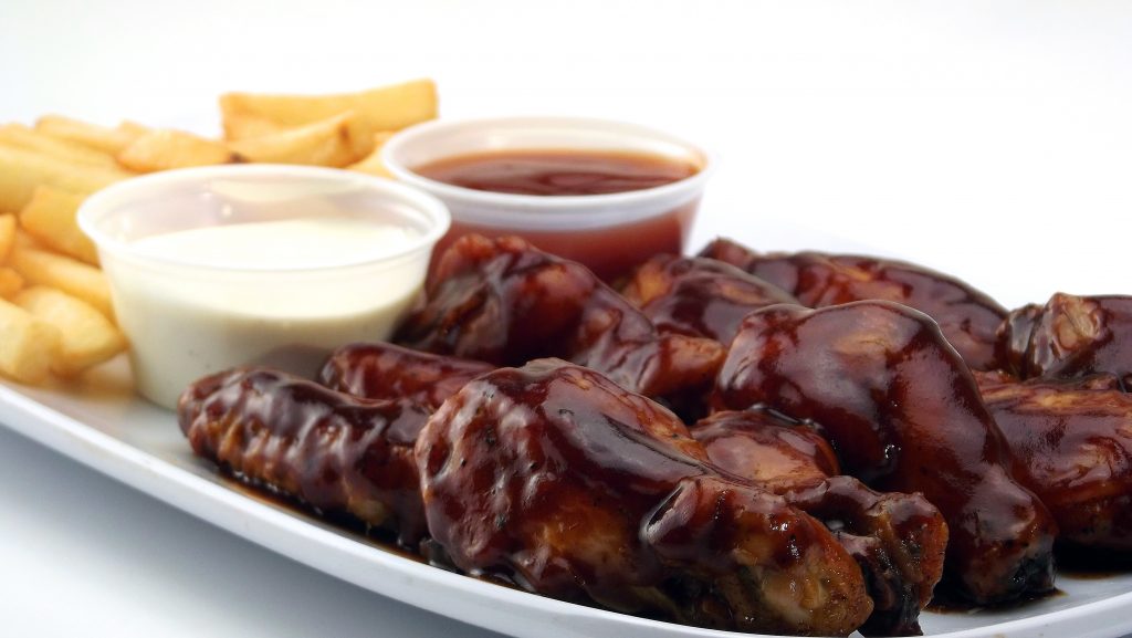 BBQ Sauce Covering a Plate on Chicken Wings and Chips